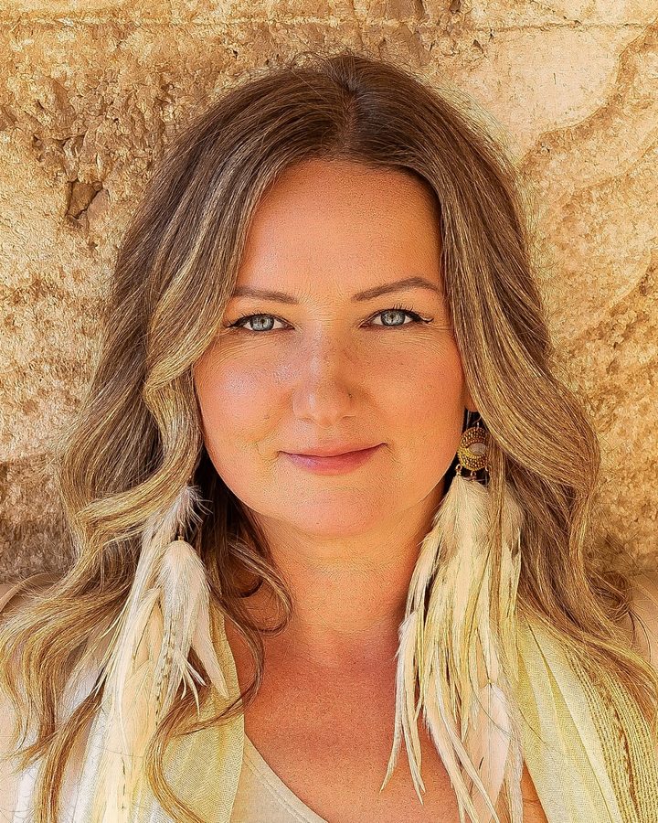 Portrait of Anya Dillon, founder of Radiant Flo, against a warm stone wall