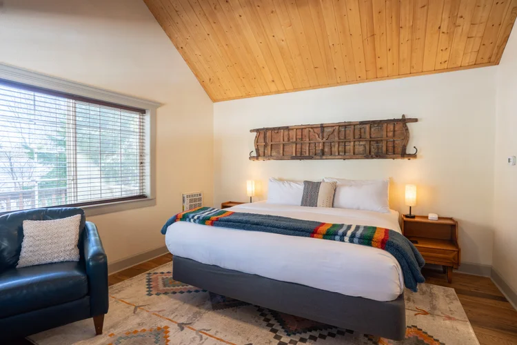 A king bed under a vaulted pine ceiling