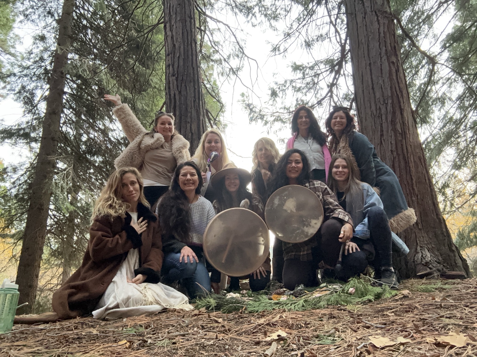 The circle gathered in the forest around the grid, frame drums in hand