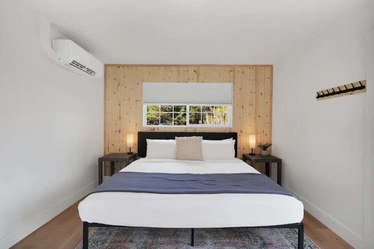 A king bed against a cedar wall, window opening to the trees
