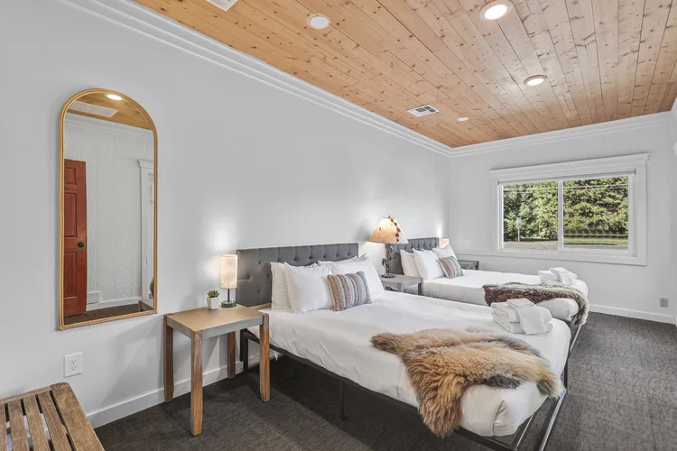 Queen beds beside a window opening to the pines
